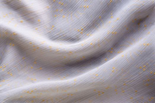 Soft folds of a light pink synthetic fabric texture with yellow gold ornaments to be used as background