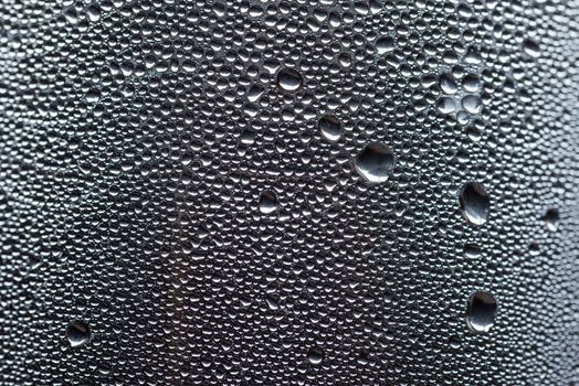 Many little water drops due to condensation on a plastic bottle curved surface