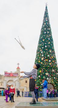 NAZARETH, ISRAEL - December 19, 2014: Jugglers, local and visitors, and a Christmas tree, in the square of the Greek Orthodox Church of Annunciation, in Nazareth, Israel