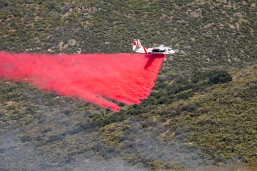 Winchester, CA USA - June 14, 2020: Cal Fire aircraft drops fire retardant on a dry hilltop wildfire near Winchester, California.