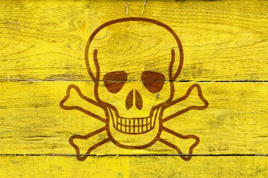 A skull as poison symbol on yellow painted pine planks