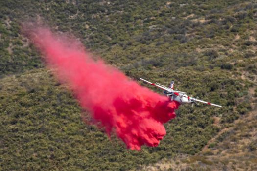 Winchester, CA USA - June 14, 2020: Cal Fire aircraft drops fire retardant on a dry hilltop wildfire near Winchester, California.