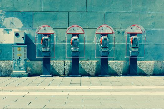 Four phone booths by the wall. Trieste, Italy