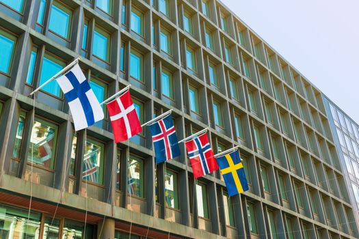 Major Scandinavian countries flags on a facade of a modern hotel building. From left to right: Finland, Denmark, Iceland, Norway, Sweden