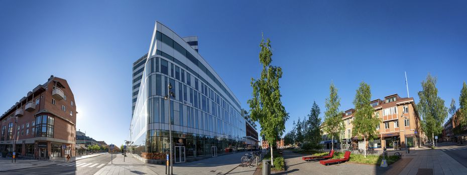 UMEA, SWEDEN - JUNE 10, 2020: Scenic panorama of downtown - nice mixture of modern and old buildings. Early sunny summer day, no people, bright colors of modern architecture and birches, Vasterbotten