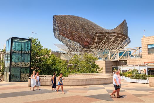 BARCELONA, SPAIN - June 21, 2017 : in the middle of the day, tourists stroll in front of the fish of the American architect Frank Gehry built on the occasion of the 1992 summer Olympics