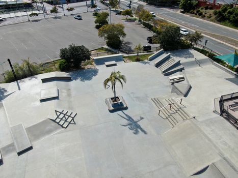 Aerial view of outdoor empty concrete skate park with ramps and pipes in California. USA