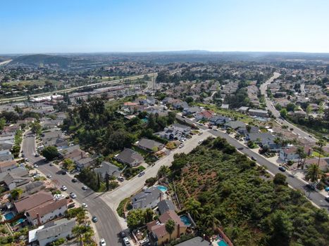 Aerial view of upper middle class neighborhood with residential house and swimming pool in a valley with mountain on the background in San Diego, California, USA.