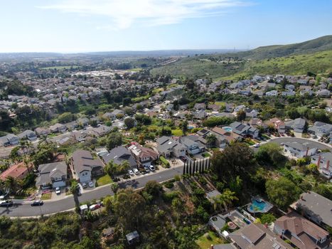 Aerial view of upper middle class neighborhood with residential house and swimming pool in a valley with mountain on the background in San Diego, California, USA.