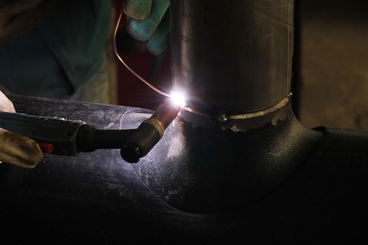 Welder Worker Performs Jump Welding. Worker Welder Performs Arc-Welding Process of Metal Structures. Flying Sparks From the Welding Machine. Welder Welds Metal Profiles for Second Floor Indoors