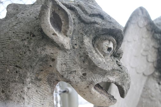 Gargoyle or chimera on the Cathedral of Notre Dame de Paris looks at the Eiffel Tower, Paris, France. Gargoyles are the Gothic landmarks in Paris. Vintage skyline of Paris with an old demon statue.