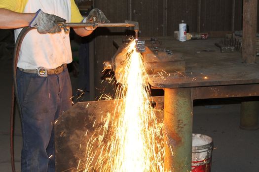 Worker is cutting manually old metal construction in container by using gas mixture of oxygen and acetylene, propane for repair work.