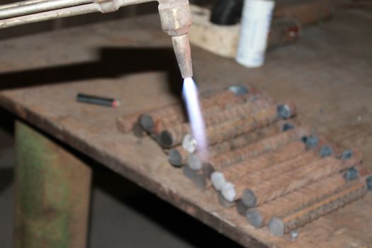 Worker is cutting manually old metal construction in container by using gas mixture of oxygen and acetylene, propane for repair work.