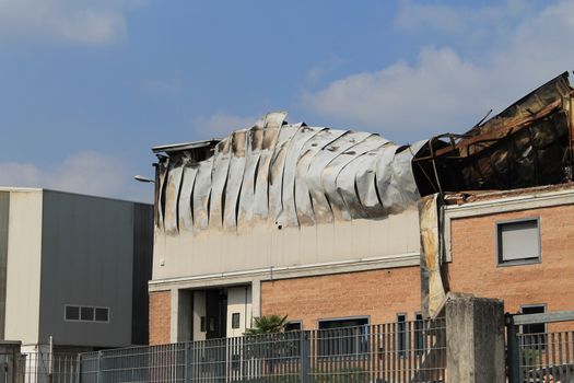 Facade of an industrial building after a fire against a blue sky