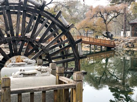 Water mill wheel in a calm little river and little pavilion on the background at The Imperial Summer Palace of The Mountain Resort in Chengde. China. 