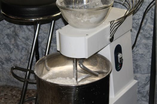 Mixing dough for bread baking with professional kneader spiral machine at the manufacturing. The dough is kneaded for burgers.