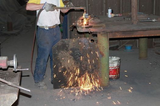 Worker is cutting manually old metal construction in container by using gas mixture of oxygen and acetylene, propane for repair work.