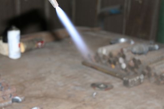 Worker is cutting manually old metal construction in container by using gas mixture of oxygen and acetylene, propane for repair work.