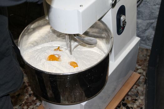 Mixing dough for bread baking with professional kneader spiral machine at the manufacturing. The dough is kneaded for burgers.