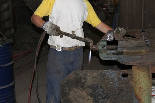 Worker is cutting manually old metal construction in container by using gas mixture of oxygen and acetylene, propane for repair work.