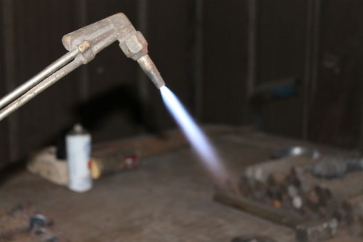 Worker is cutting manually old metal construction in container by using gas mixture of oxygen and acetylene, propane for repair work.