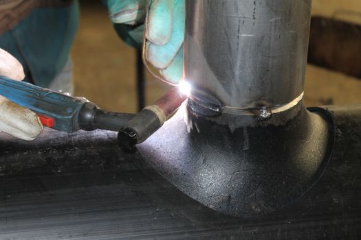 Welder Worker Performs Jump Welding. Worker Welder Performs Arc-Welding Process of Metal Structures. Flying Sparks From the Welding Machine. Welder Welds Metal Profiles for Second Floor Indoors