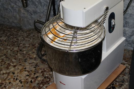 Mixing dough for bread baking with professional kneader spiral machine at the manufacturing. The dough is kneaded for burgers.