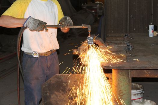 Worker is cutting manually old metal construction in container by using gas mixture of oxygen and acetylene, propane for repair work.