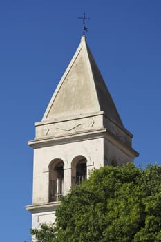 church tower above the tree, with the blue sky in the background