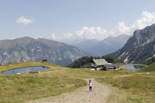 Scenic view to small alpine lake and big mountains with glacier in sunlight. Awesome green landscape with blue mountain lake among mosses in green highland valley in sunny day. Wonderful scenery.