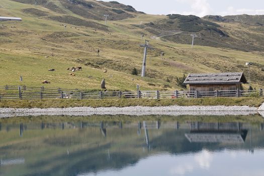 Scenic view to small alpine lake and big mountains with glacier in sunlight. Awesome green landscape with blue mountain lake among mosses in green highland valley in sunny day. Wonderful scenery.