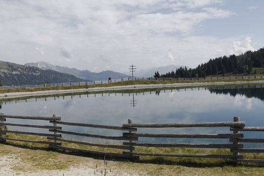 Scenic view to small alpine lake and big mountains with glacier in sunlight. Awesome green landscape with blue mountain lake among mosses in green highland valley in sunny day. Wonderful scenery.