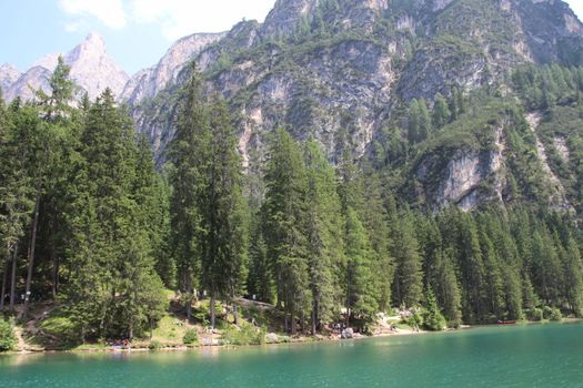 Braies Lake in Dolomites mountains forest trail in background, Sudtirol, Italy. Lake Braies is also known as Lago di Braies. The lake is surrounded by forest which are famous for scenic hiking trails.