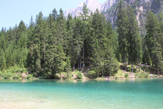 Braies Lake in Dolomites mountains forest trail in background, Sudtirol, Italy. Lake Braies is also known as Lago di Braies. The lake is surrounded by forest which are famous for scenic hiking trails.