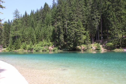 Braies Lake in Dolomites mountains forest trail in background, Sudtirol, Italy. Lake Braies is also known as Lago di Braies. The lake is surrounded by forest which are famous for scenic hiking trails.