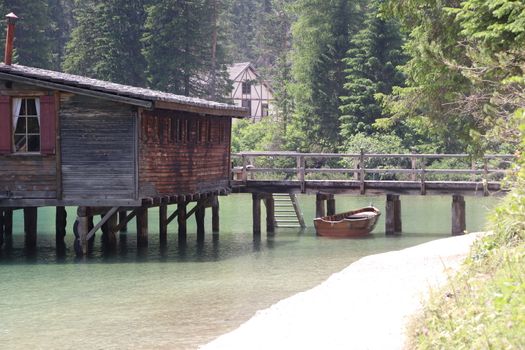 Braies Lake in Dolomites mountains forest trail in background, Sudtirol, Italy. Lake Braies is also known as Lago di Braies. The lake is surrounded by forest which are famous for scenic hiking trails.