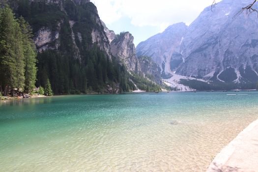 Braies Lake in Dolomites mountains forest trail in background, Sudtirol, Italy. Lake Braies is also known as Lago di Braies. The lake is surrounded by forest which are famous for scenic hiking trails.