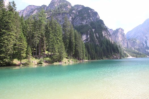 Braies Lake in Dolomites mountains forest trail in background, Sudtirol, Italy. Lake Braies is also known as Lago di Braies. The lake is surrounded by forest which are famous for scenic hiking trails.