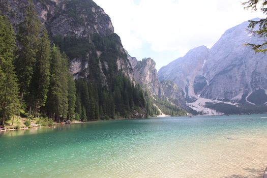 Braies Lake in Dolomites mountains forest trail in background, Sudtirol, Italy. Lake Braies is also known as Lago di Braies. The lake is surrounded by forest which are famous for scenic hiking trails.