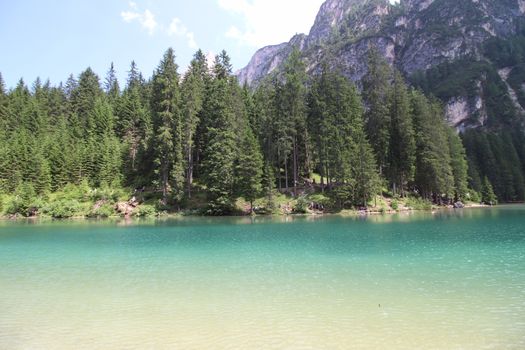 Braies Lake in Dolomites mountains forest trail in background, Sudtirol, Italy. Lake Braies is also known as Lago di Braies. The lake is surrounded by forest which are famous for scenic hiking trails.