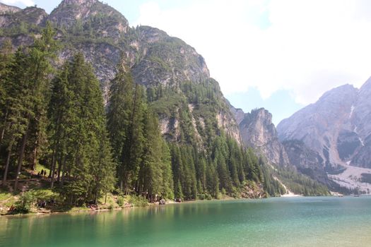 Braies Lake in Dolomites mountains forest trail in background, Sudtirol, Italy. Lake Braies is also known as Lago di Braies. The lake is surrounded by forest which are famous for scenic hiking trails.