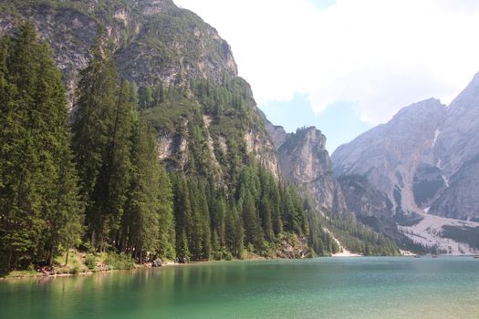 Braies Lake in Dolomites mountains forest trail in background, Sudtirol, Italy. Lake Braies is also known as Lago di Braies. The lake is surrounded by forest which are famous for scenic hiking trails.