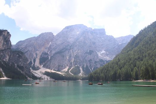 Braies Lake in Dolomites mountains forest trail in background, Sudtirol, Italy. Lake Braies is also known as Lago di Braies. The lake is surrounded by forest which are famous for scenic hiking trails.