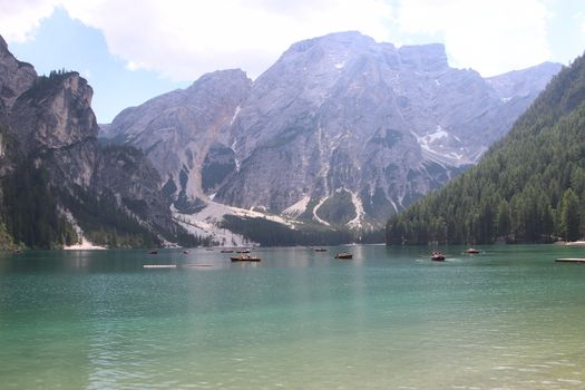 Braies Lake in Dolomites mountains forest trail in background, Sudtirol, Italy. Lake Braies is also known as Lago di Braies. The lake is surrounded by forest which are famous for scenic hiking trails.