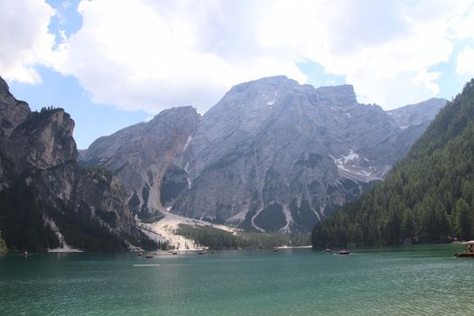 Braies Lake in Dolomites mountains forest trail in background, Sudtirol, Italy. Lake Braies is also known as Lago di Braies. The lake is surrounded by forest which are famous for scenic hiking trails.