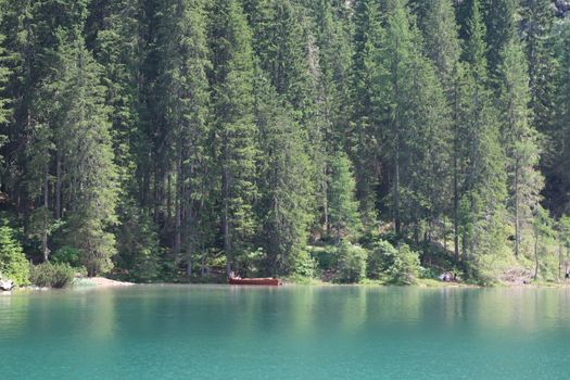 Braies Lake in Dolomites mountains forest trail in background, Sudtirol, Italy. Lake Braies is also known as Lago di Braies. The lake is surrounded by forest which are famous for scenic hiking trails.