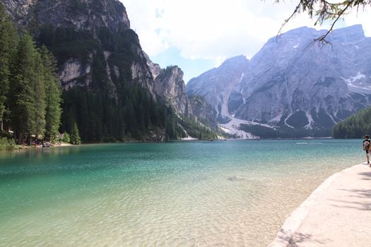 Braies Lake in Dolomites mountains forest trail in background, Sudtirol, Italy. Lake Braies is also known as Lago di Braies. The lake is surrounded by forest which are famous for scenic hiking trails.