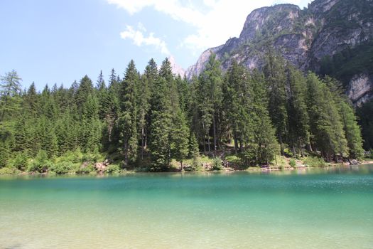 Braies Lake in Dolomites mountains forest trail in background, Sudtirol, Italy. Lake Braies is also known as Lago di Braies. The lake is surrounded by forest which are famous for scenic hiking trails.