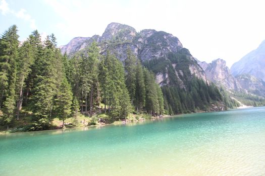 Braies Lake in Dolomites mountains forest trail in background, Sudtirol, Italy. Lake Braies is also known as Lago di Braies. The lake is surrounded by forest which are famous for scenic hiking trails.