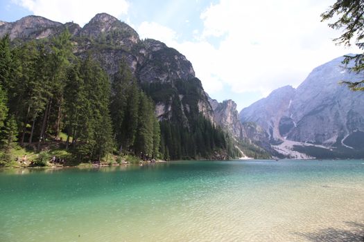 Braies Lake in Dolomites mountains forest trail in background, Sudtirol, Italy. Lake Braies is also known as Lago di Braies. The lake is surrounded by forest which are famous for scenic hiking trails.